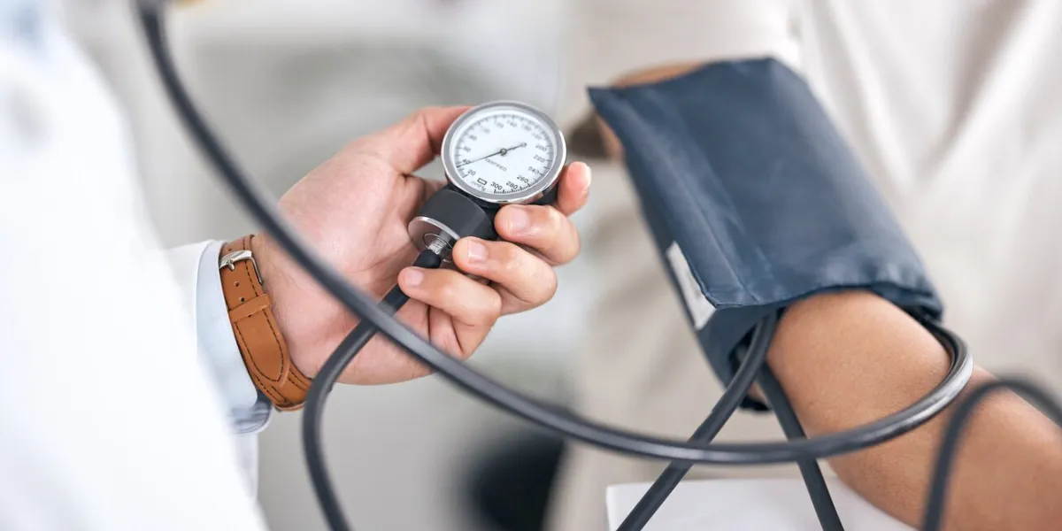 hands, blood pressure and doctor with patient in consultation at hospital in clinic test hypertension, exam and arm of person with medical professional for check up for heart health, advice and care