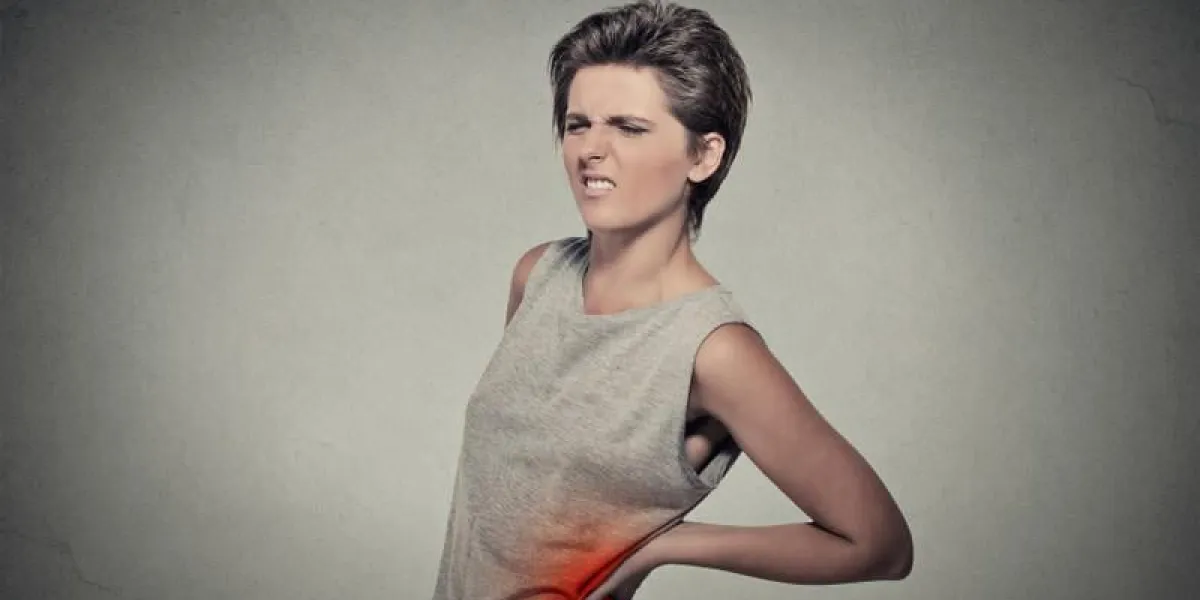 jeune femme avec maux de dos mal de dos dos coloré en rouge isolé sur fond gris