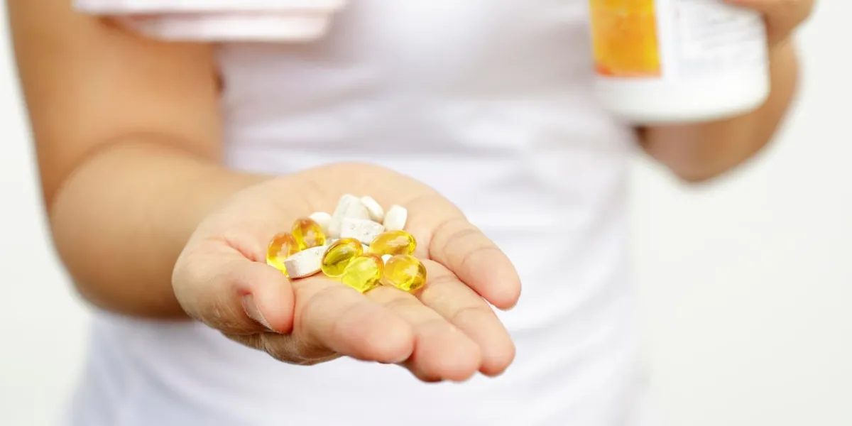 sport and diet concept - woman hand with vitamins and medication