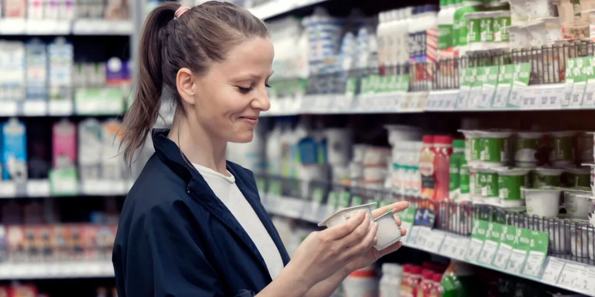 a young smiling lady chooses and buys yogurts in a store