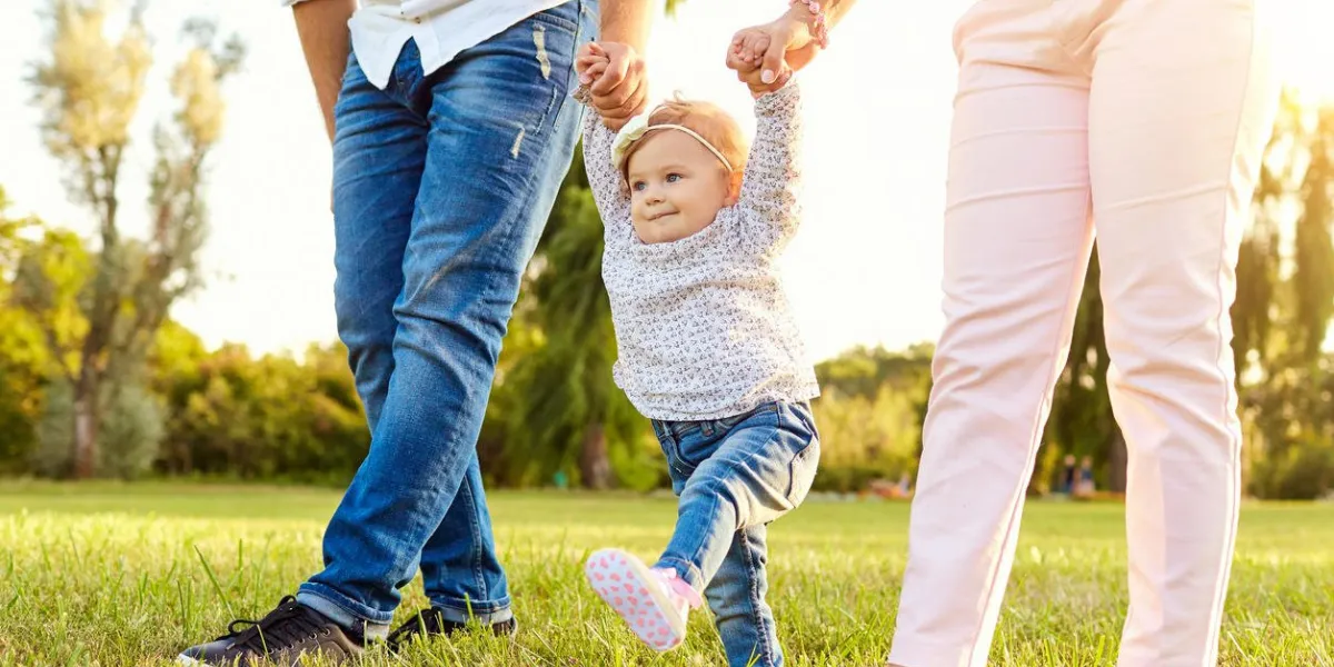 the first steps of the baby parents are teaching their child to walk a happy family
