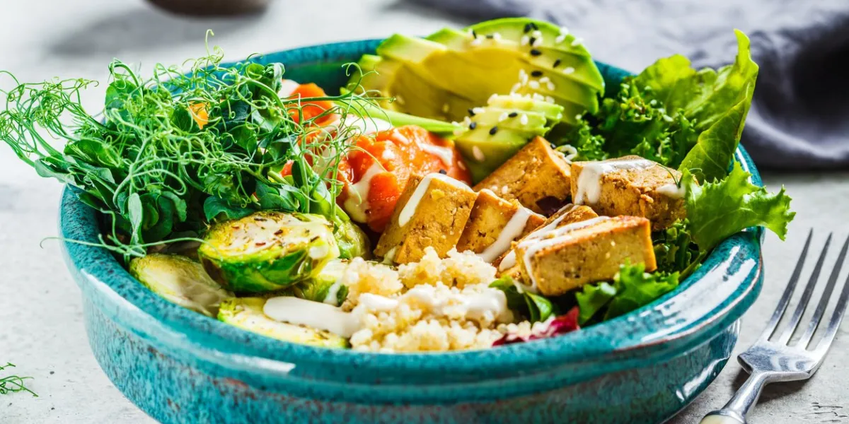 buddha bowl with quinoa, tofu, avocado, sweet potato, brussels sprouts and tahini dressing healthy vegan food concept