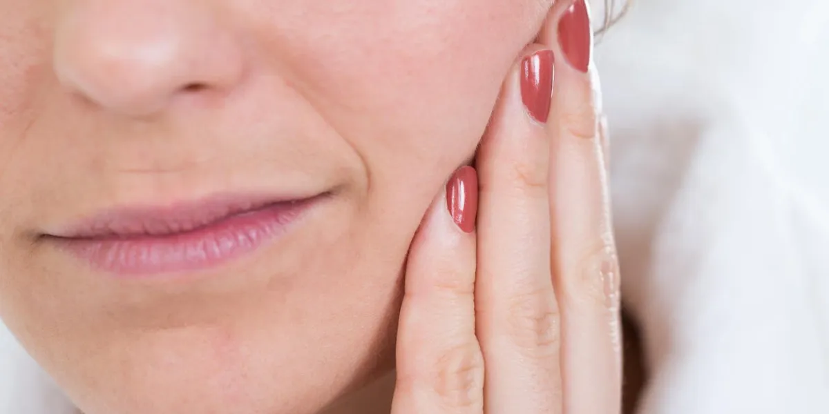 gros plan d'une femme avec des maux de dents touchant le visage