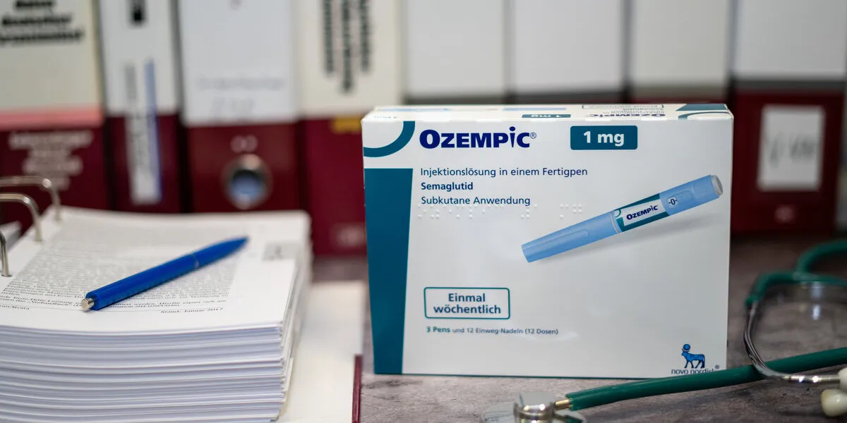 a drug box of ozempic containing semaglutide for treatment of type 2 diabetes and long-term weight management on a table and in the background different medical books