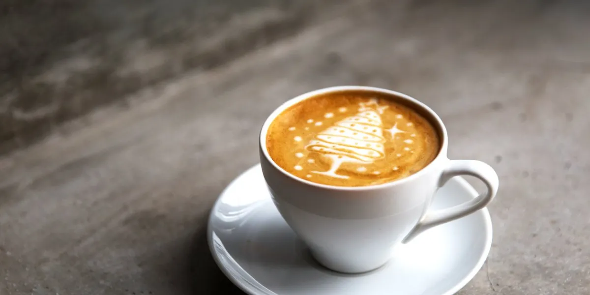 tasty cappuccino with christmas tree latte art with some blurred lights holiday concept