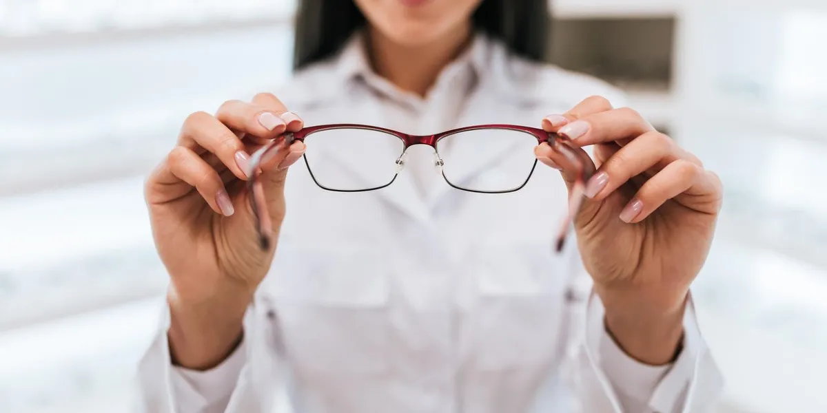 cropped image of attractive young female doctor in ophthalmology clinic doctor ophthalmologist is standing near shelves with different eyeglasses