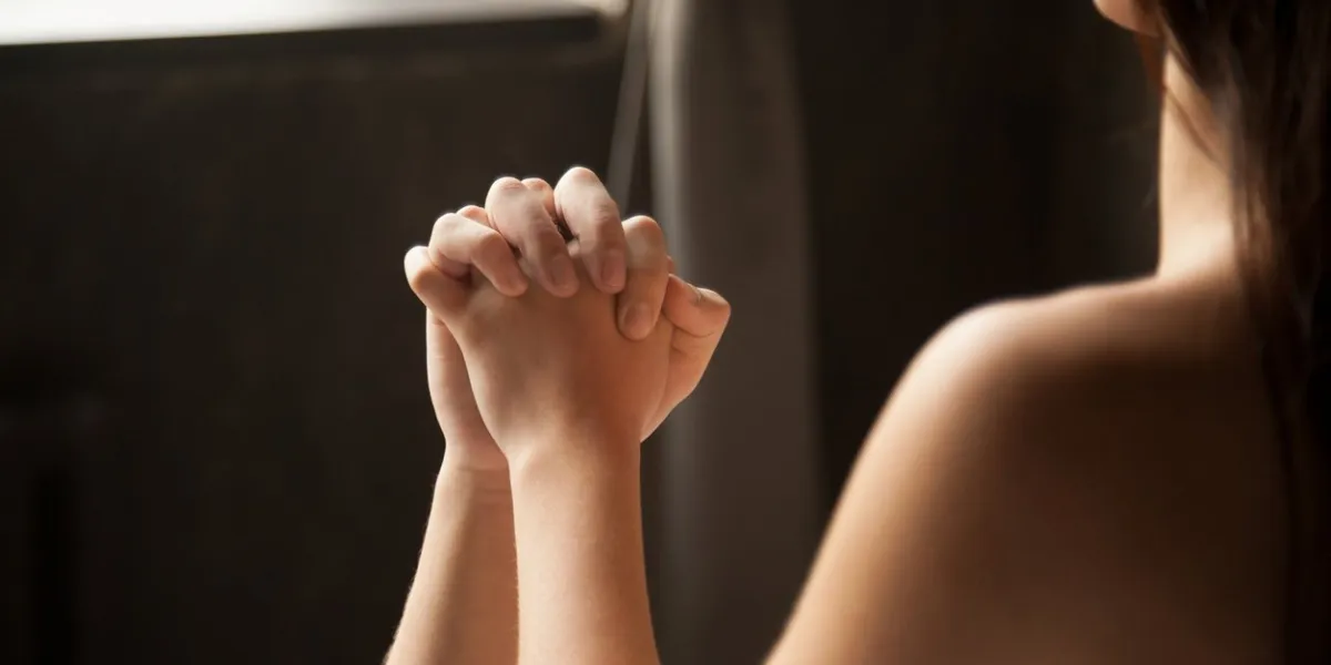 heterosexual couple in bedroom female and male hands during having sex hand close up view over the womans naked shirtless shoulder concept of passion and desire, feelings, love, ecstasy and orgasm