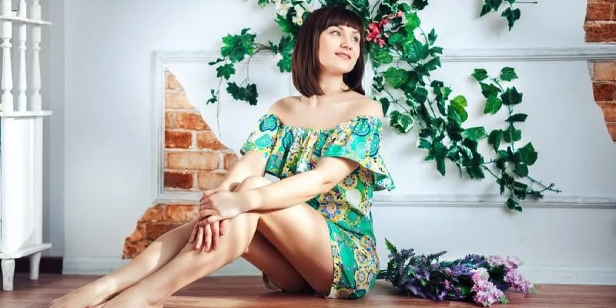 jeune femme dans une robe brillante est assis sur le sol sur un fond de fleurs