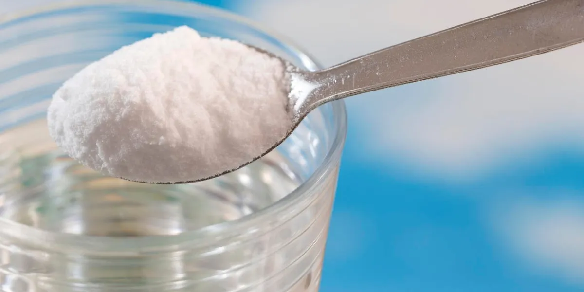 cuillère de bicarbonate de soude tombant dans un verre d'eau