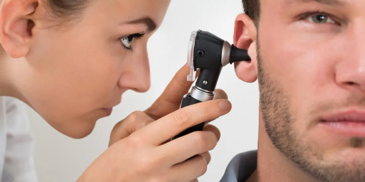 médecin regardant dans l'oreille du patient avec un instrument