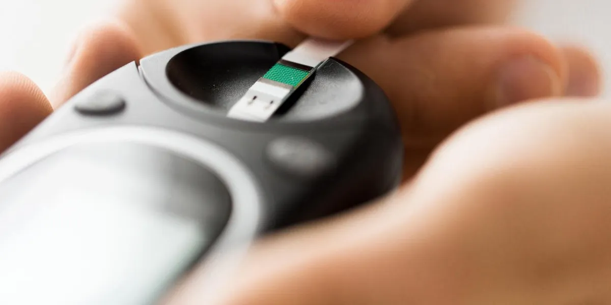 concept de médecine, de diabète, de glycémie, de soins de santé et de personnes - gros plan de l'homme vérifiant le niveau de sucre dans le sang par glucomètre et bande de test à la maison