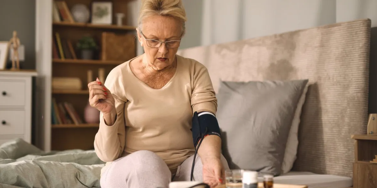 senior woman measuring blood pressure in bedroom