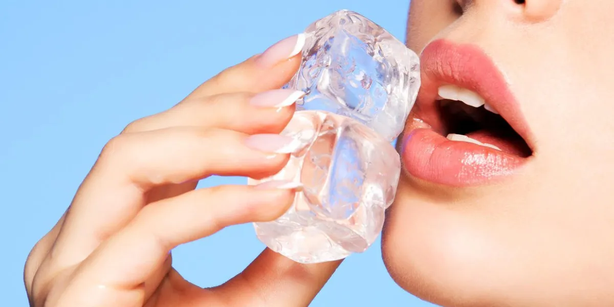 closeup portrait de belle jeune femme applique la glace pour faire face sur un fond bleu