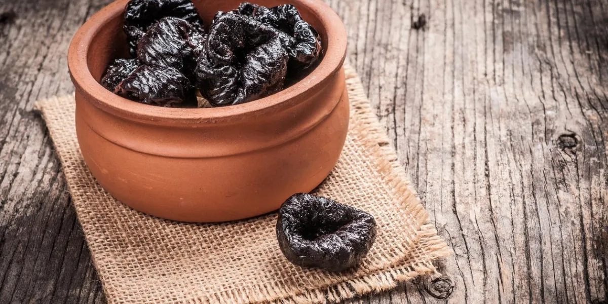 pruneaux dans un bol sur le lin et le bois rustique