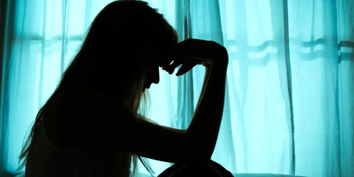 silhouette of woman sitting in bed by window