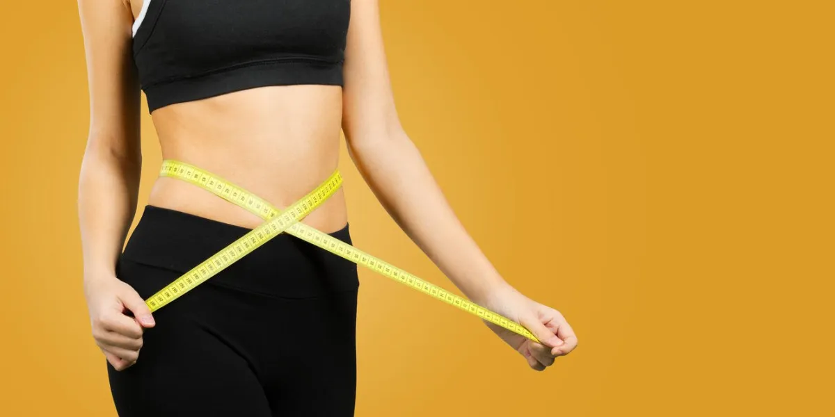 slim young woman measuring her waist