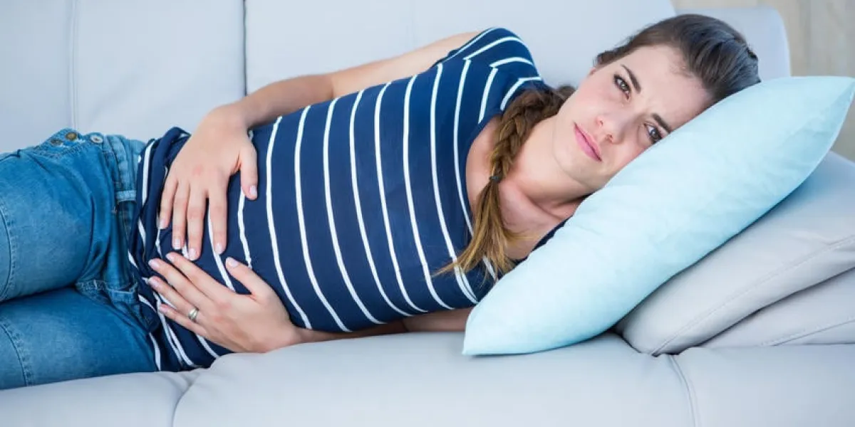 jolie brune souffrant de douleurs à l'estomac à la maison dans la chambre