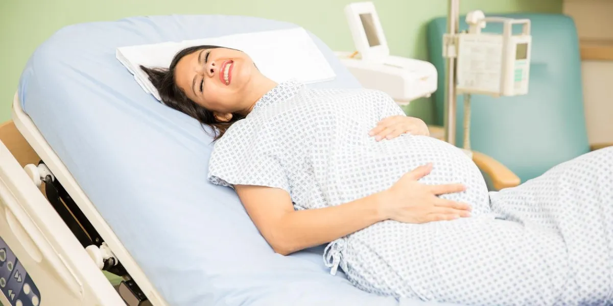 pretty young pregnant woman getting labor contractions while lying on a hospital bed