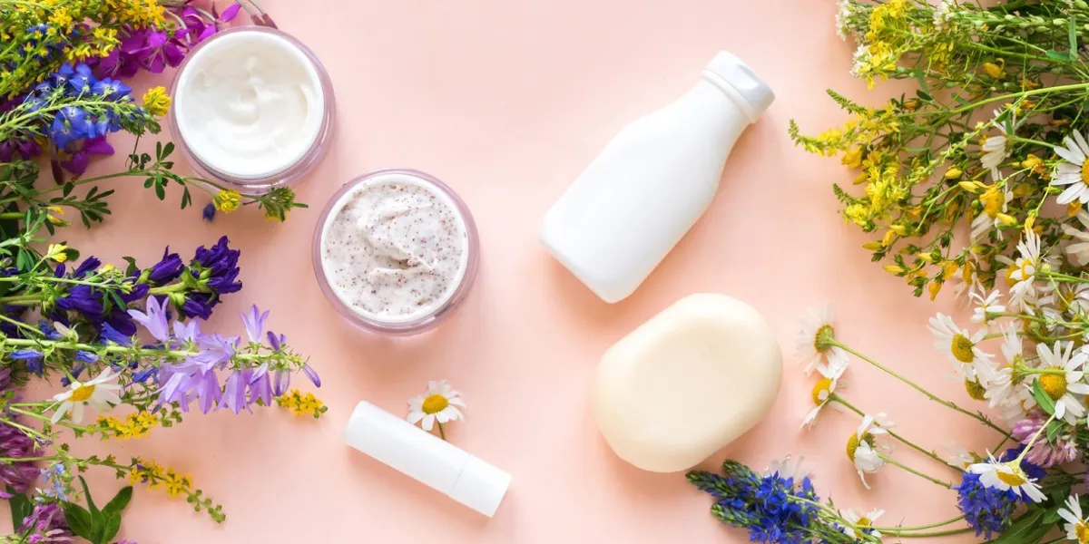 eco friendly skincare natural cosmetics and organic herbs and flowers on pink background, top view, banner bio research and healthy lifestyle concept
