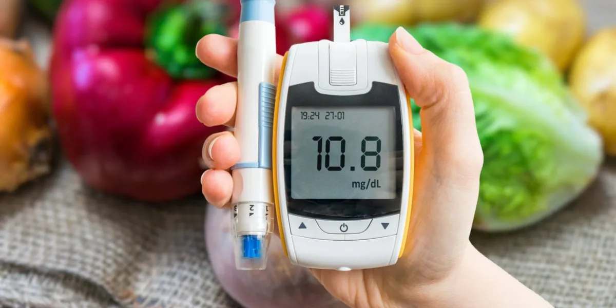 diabetic diet and diabetes concept hand holds glucometer vegetables in background