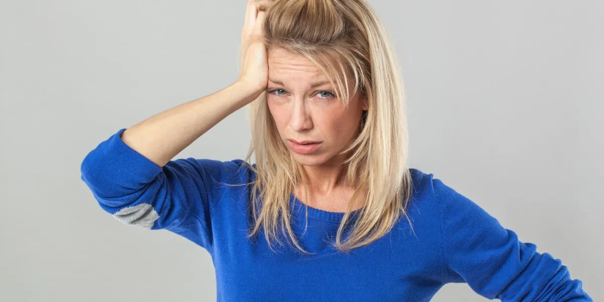 concept de gueule de bois ou insomnie - malade jeune femme blonde avec des sacs se gratter les cheveux pour mal de tête, studio shot
