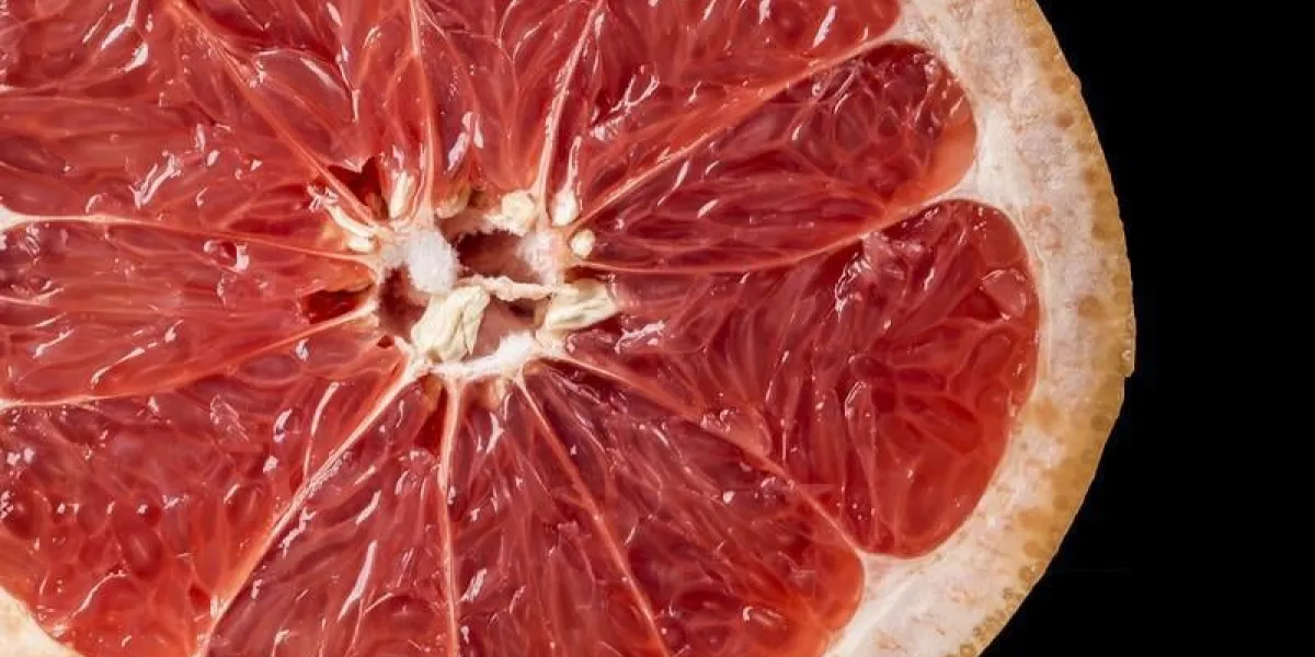 fond de tranche de pamplemousse mûr sur fond noir, texture de fruits frais