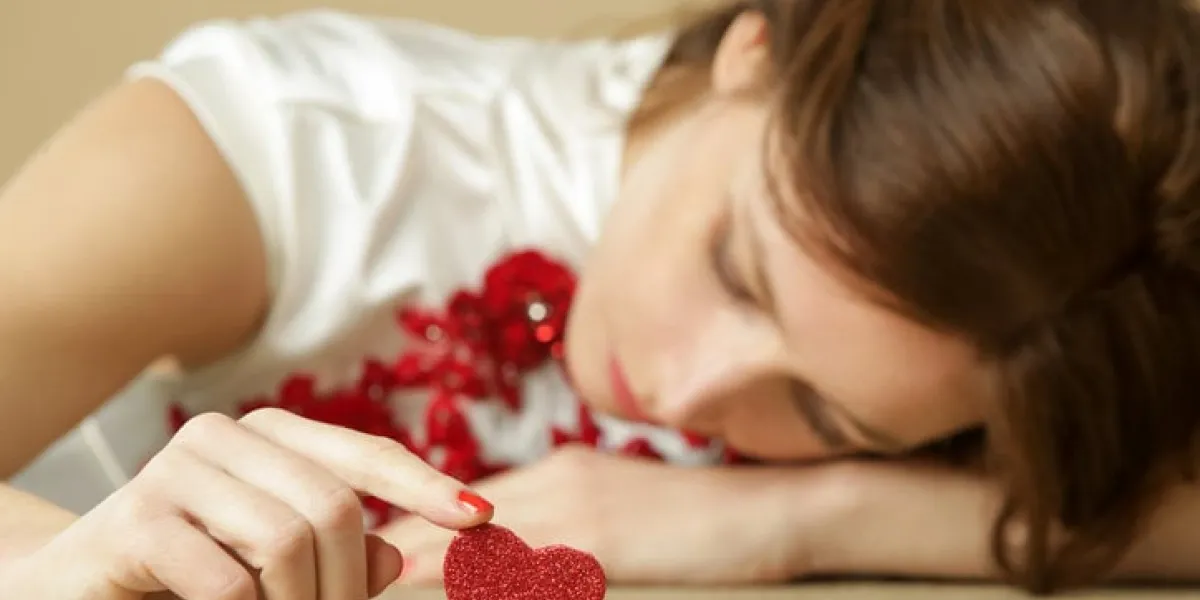 sad lonely woman holding red heart being alone on valentine's day heartbreak, divorce or breakup concept