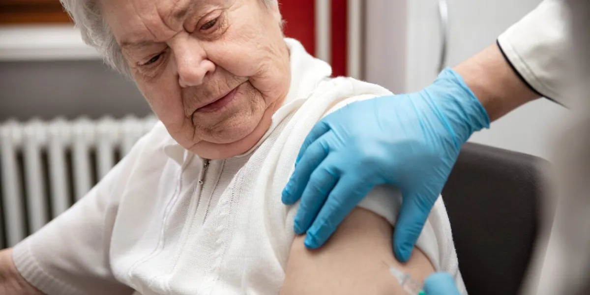 senior adult elderly woman with grey hair is receiving a vaccination against covid, concept pandemic coronavirus protection or flu