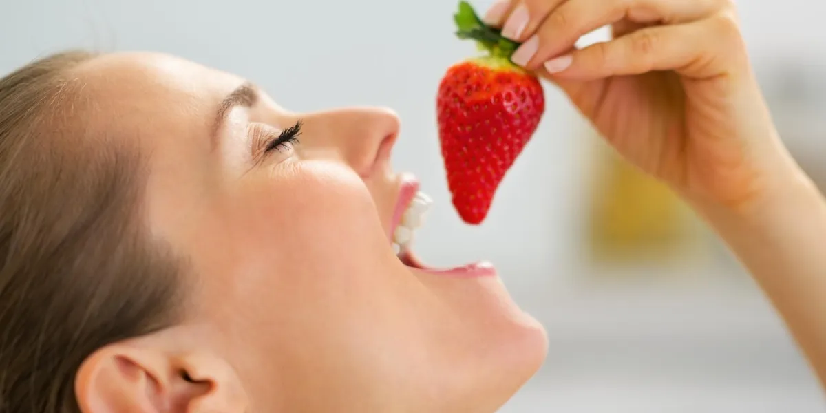 portrait de jeune femme mangeant des fraises