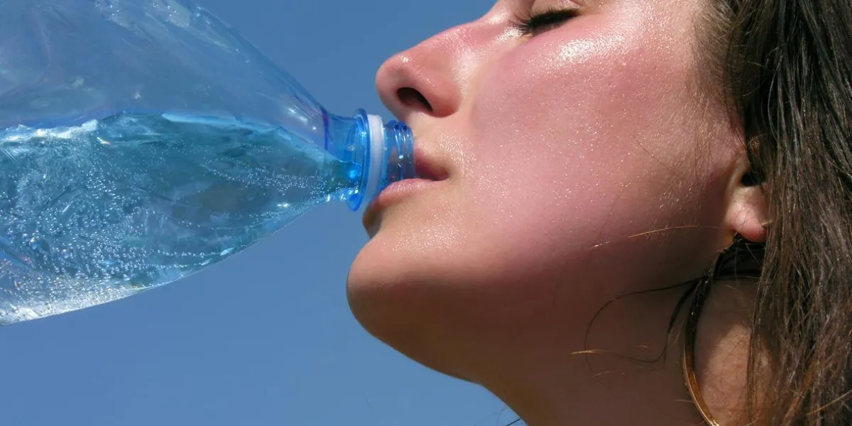 jeune femme brûlée par le soleil, boire de l'eau froide
