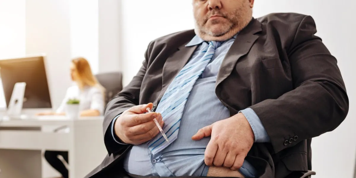 consequents of excessiveness stout sad compulsive guy suffering from his excess weight causing him a lot of trouble and preparing doing an injection