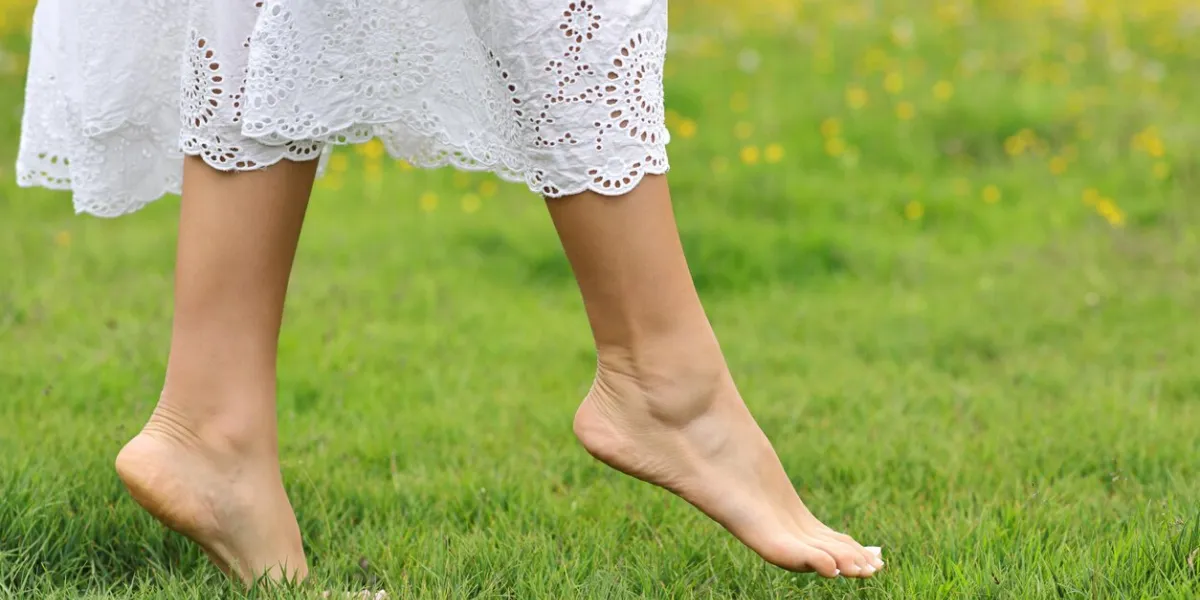 woman bare feet walking on the grass in the mountain