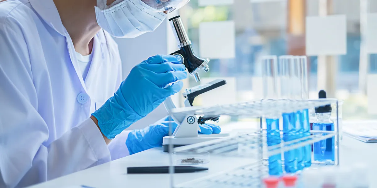 medical or scientific researcher or man doctor looking at a test tube of clear solution in a laboratory