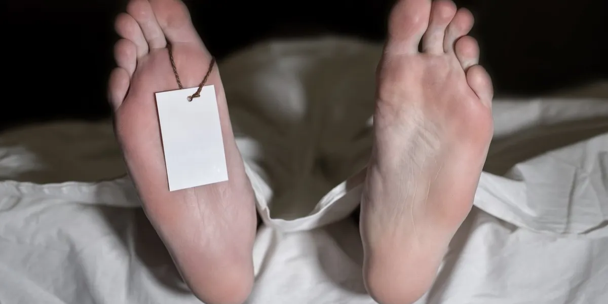 dead man lying on the floor under white cloth with blank tag on feet - retro style the concept of what people die from