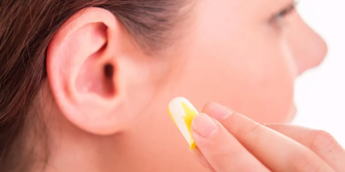 femme appliquer des bouchons d'oreille dans l'oreille - gros plan