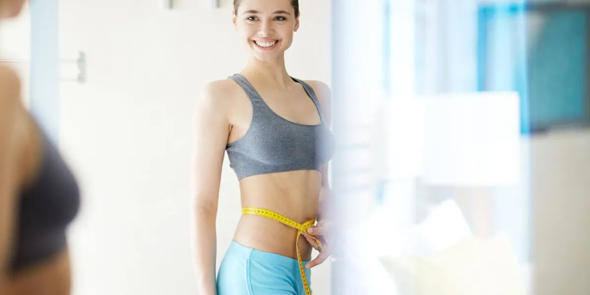 jeune femme mesurant sa taille devant le miroir