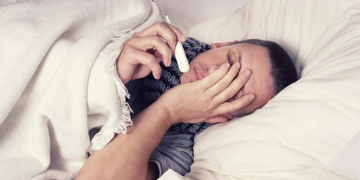 mann liegt mit fieber im bett