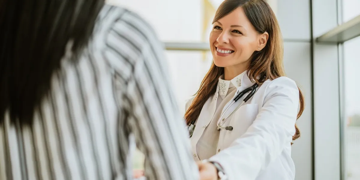 female doctor talking and touching woman patient for encouragement