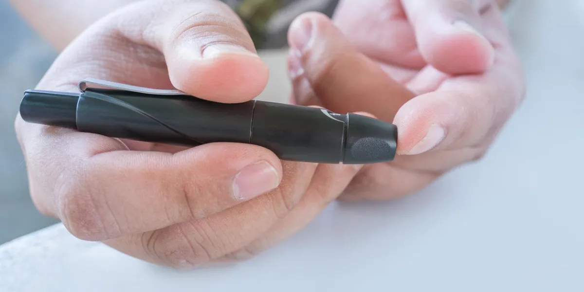 close up of male finger patient pricking his finger to draw a drop for blood testing