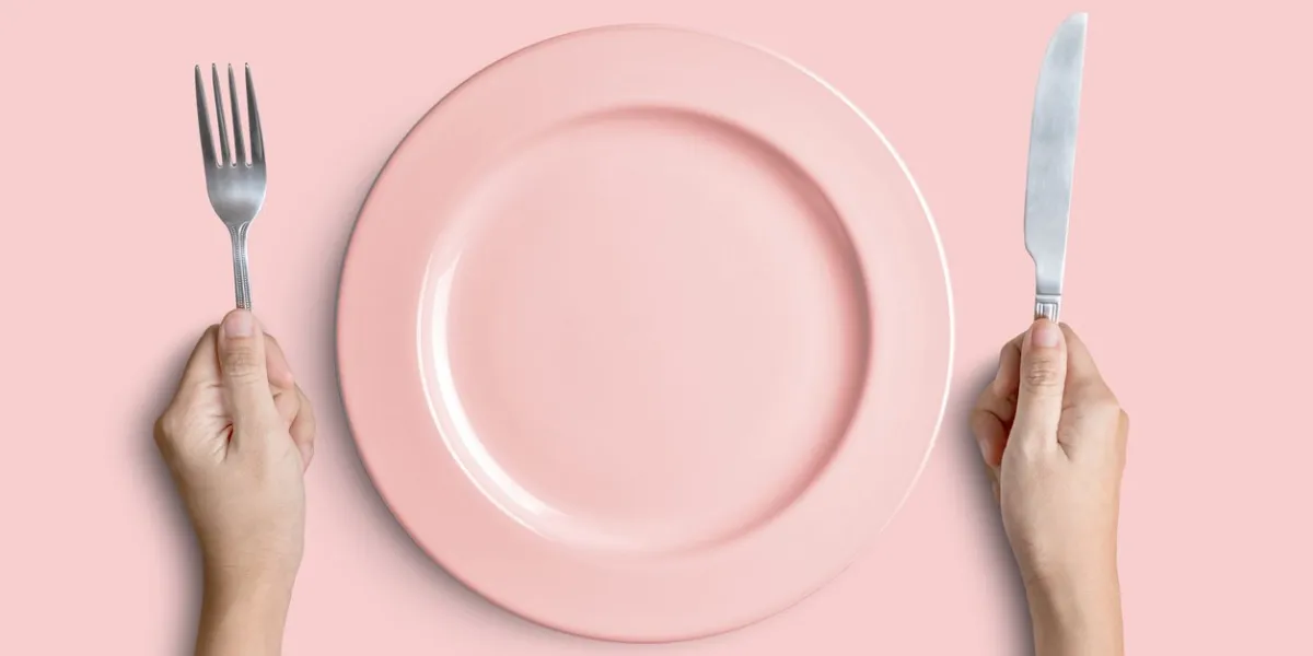 dinner place setting a pink plate with silver fork and knife isolated on pink background with clipping path