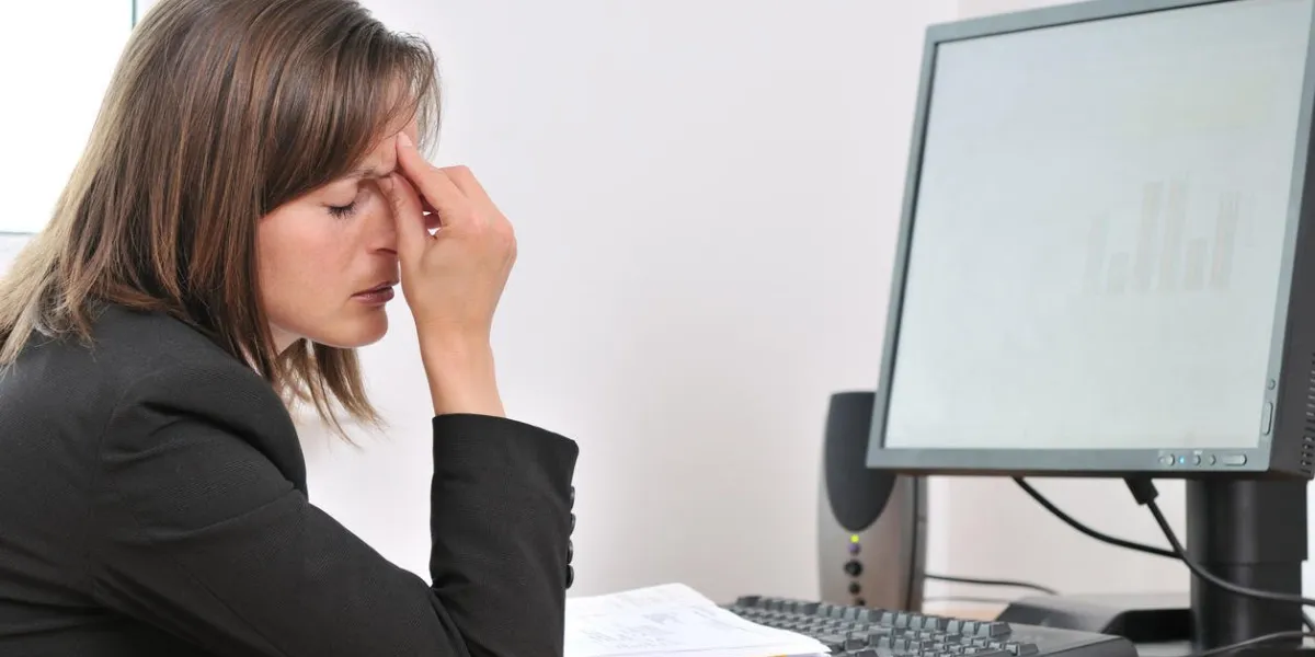 femme d'affaires jeune avec mal de tête et yeux fermés fatigués assis à l'ordinateur dans le lieu de travail