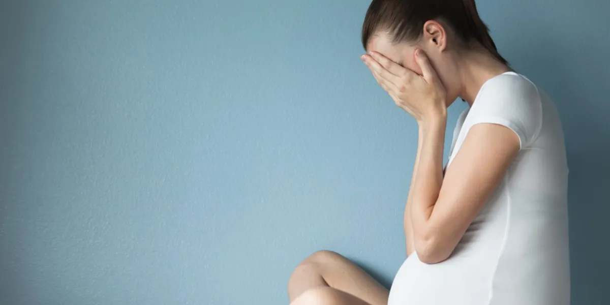 stressed pregnant woman against blue background