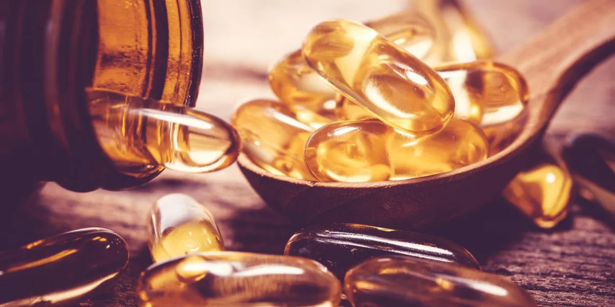 close up the vitamin d and omega 3 fish oil capsules supplement on wooden plate for good brain , heart and health eating benefit