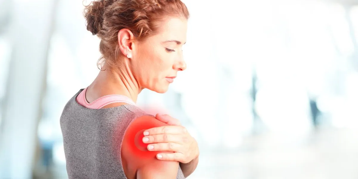 portrait of sporty woman putting her hand on red spots on while has sport injury in her shoulder