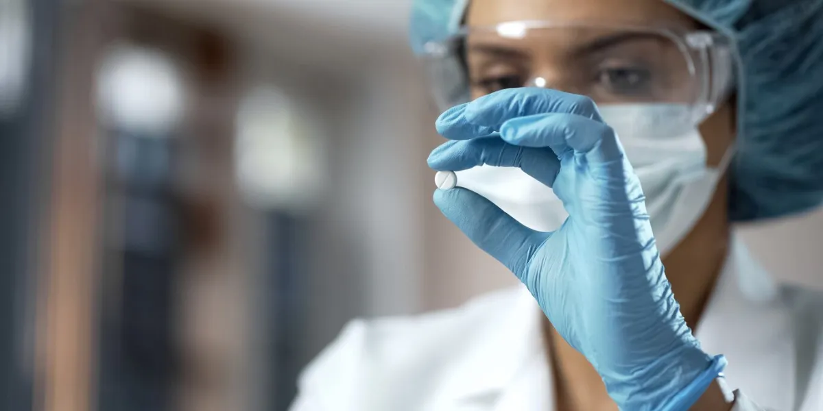 female chemist looking at white pill, new medication testing in laboratory