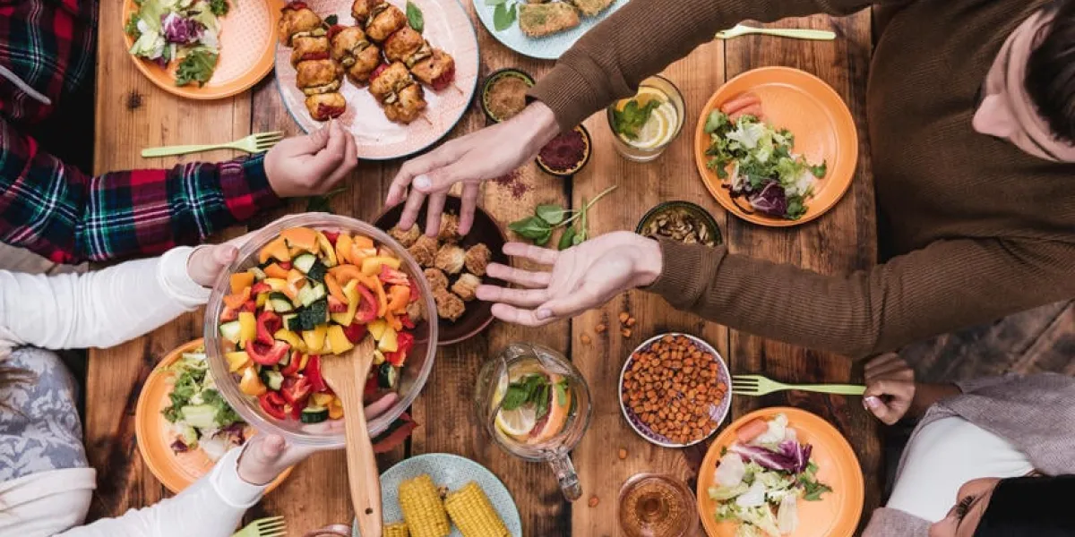 vue de dessus de quatre personnes en train de dîner ensemble assis à la table en bois rustique