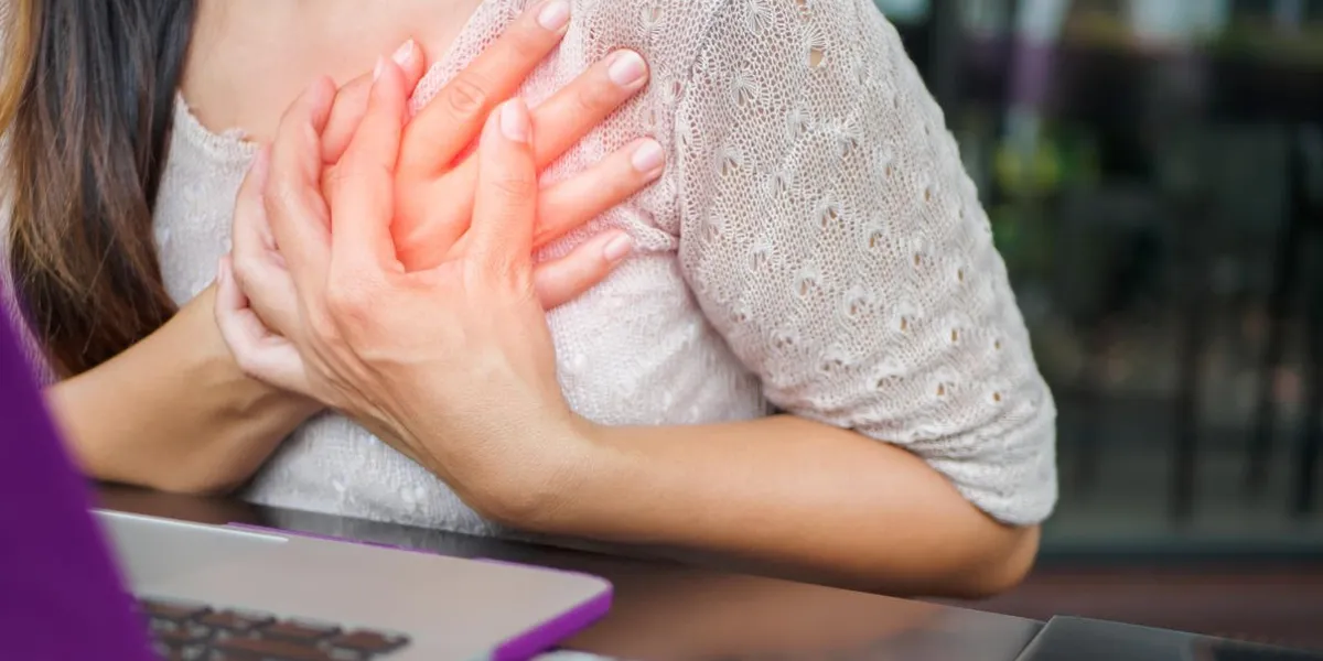 closeup woman having heart attack woman touching breast and having chest pain after long hours work on computer office syndrome concept