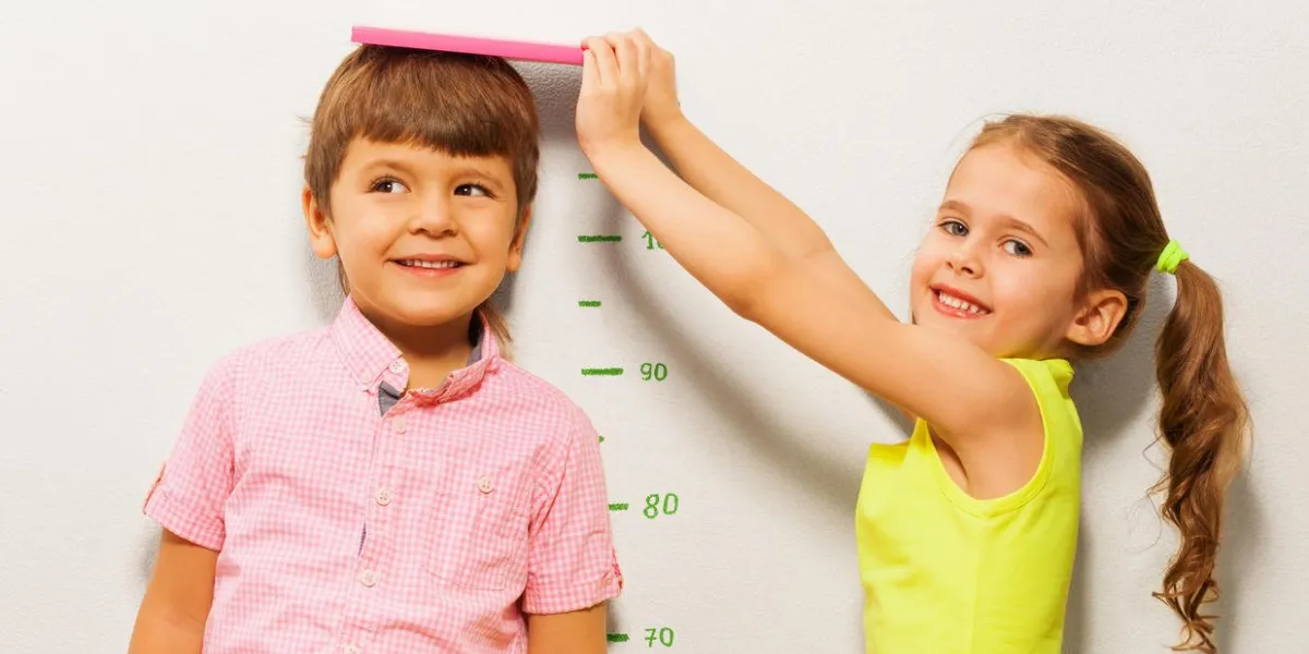 petite fille de 5 ans mesure une hauteur de garçon par échelle sur le mur