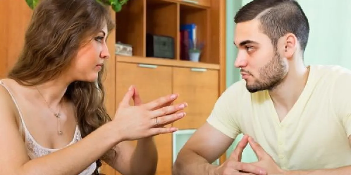 sérieux jeune couple parlant à la table à l'intérieur de la maison