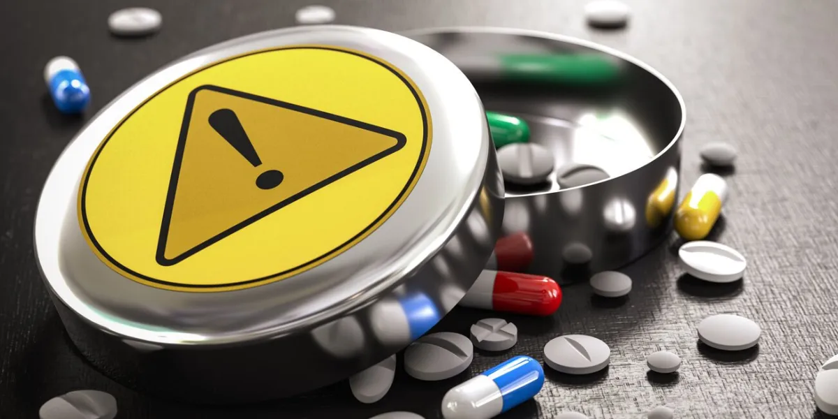 box of different pills and tablets with warning sign drug interactions and risks or adverse effects concept 3d render